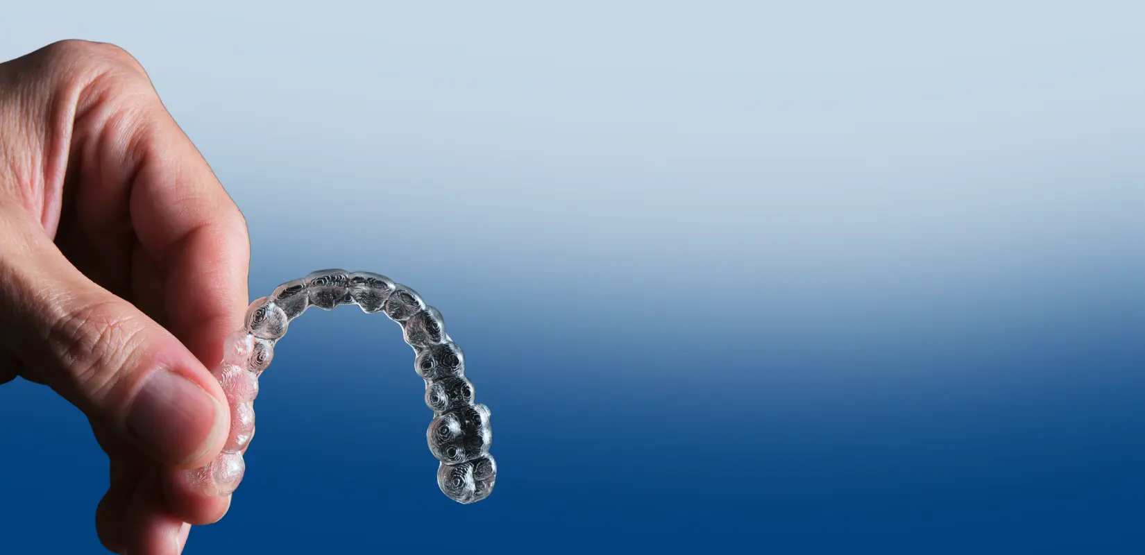 Alineador transparente de Invisalign sostenido con la mano